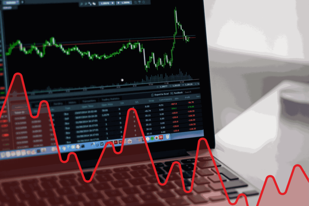 A graph showing the financial market fluctuations displayed on a laptop illustrates the differences between trading vs investing strategies.