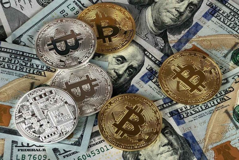 Bitcoin coins on top of US dollar bills, representing the relationship between traditional money and cryptocurrency. Key for understanding what is cryptocurrency.