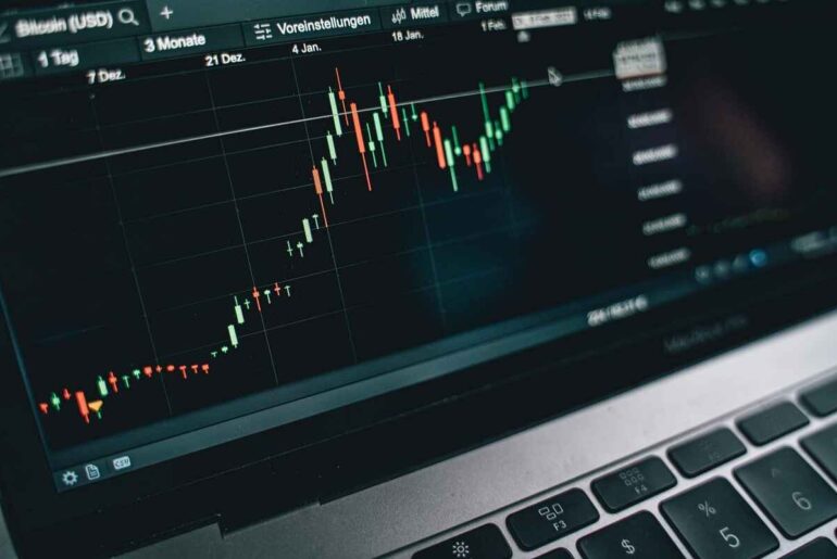 Importance of Stock Market Analysis to Boost Your Trading Success in 2025 - A laptop screen displaying a candlestick chart showing upward market trends.