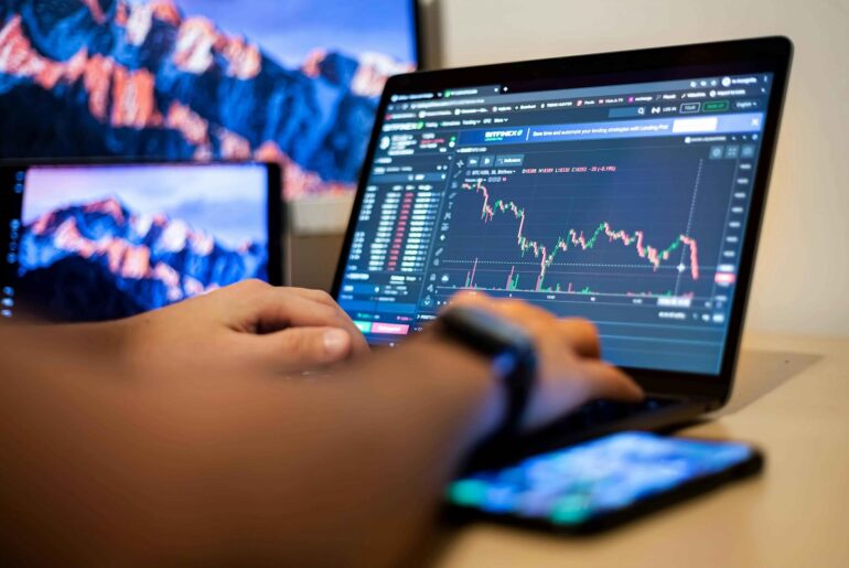 A trader analyzing a candlestick chart on a laptop focusing on stock price movements for intraday trading strategies.