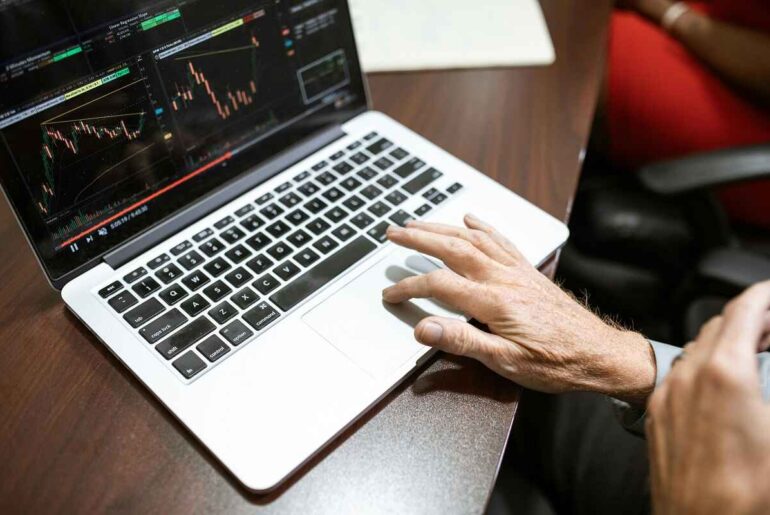 Learn Crypto Trading - A person analyzing multiple cryptocurrency trading charts on a laptop, symbolizing hands-on experience in crypto market trends.