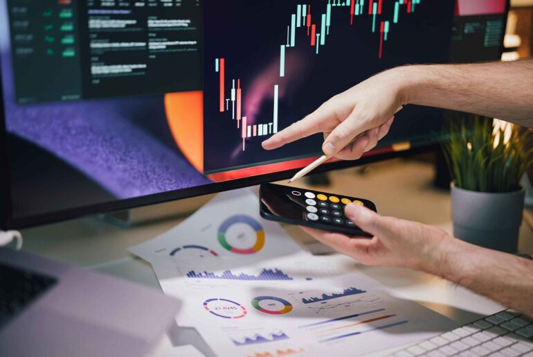 Trader analyzing candlestick chart on a large monitor while calculating data. Learn Effective Technical Analysis and Powerful Trading Strategies for success.