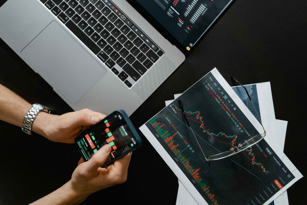 Trader analyzing stock market charts on a smartphone and laptop. Learn Effective Technical Analysis and Powerful Trading Strategies for successful trading outcomes.